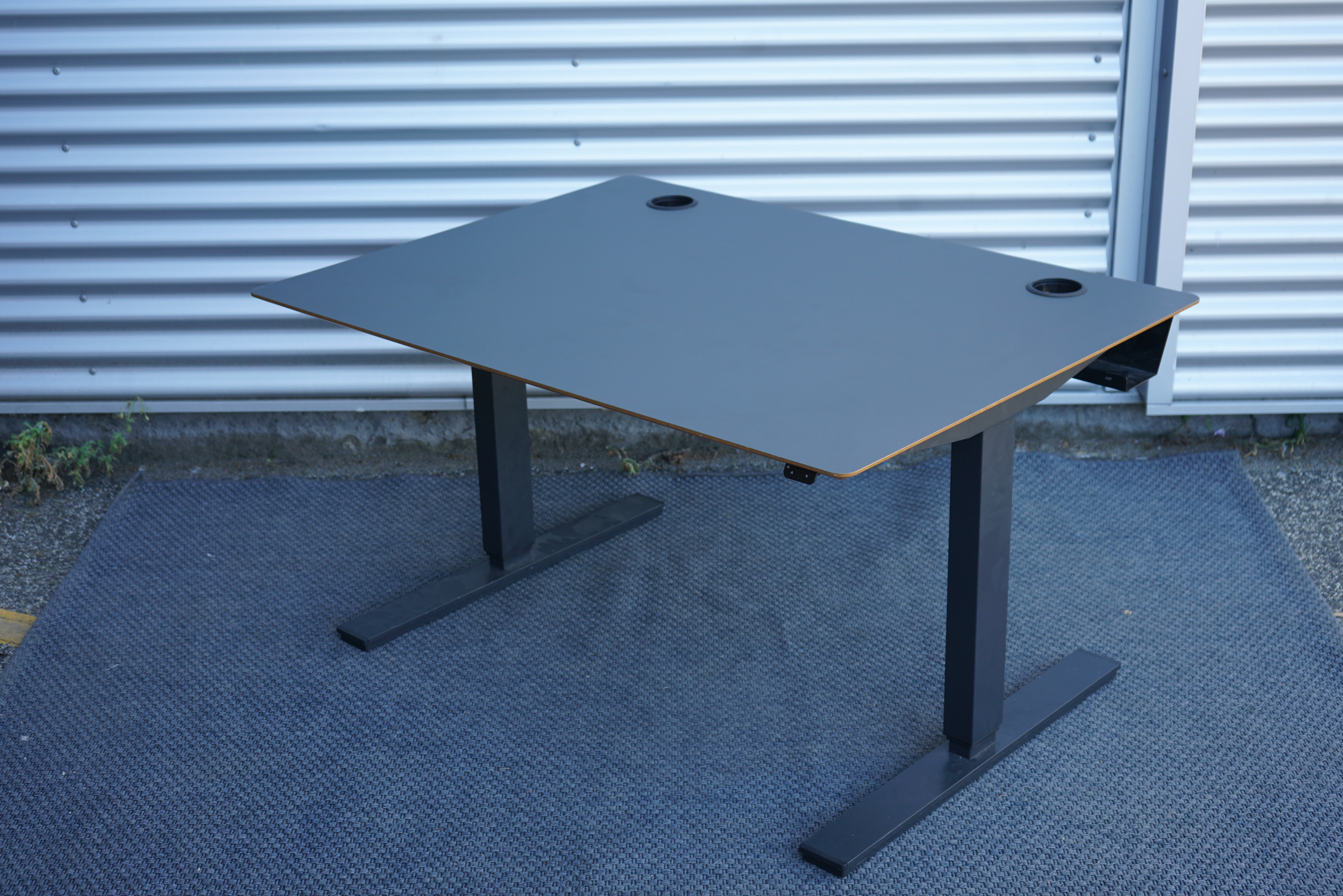 Scanoffice hæve-sænkebord i sort linoleum med trækant og sort stel set fra skrå vinkel